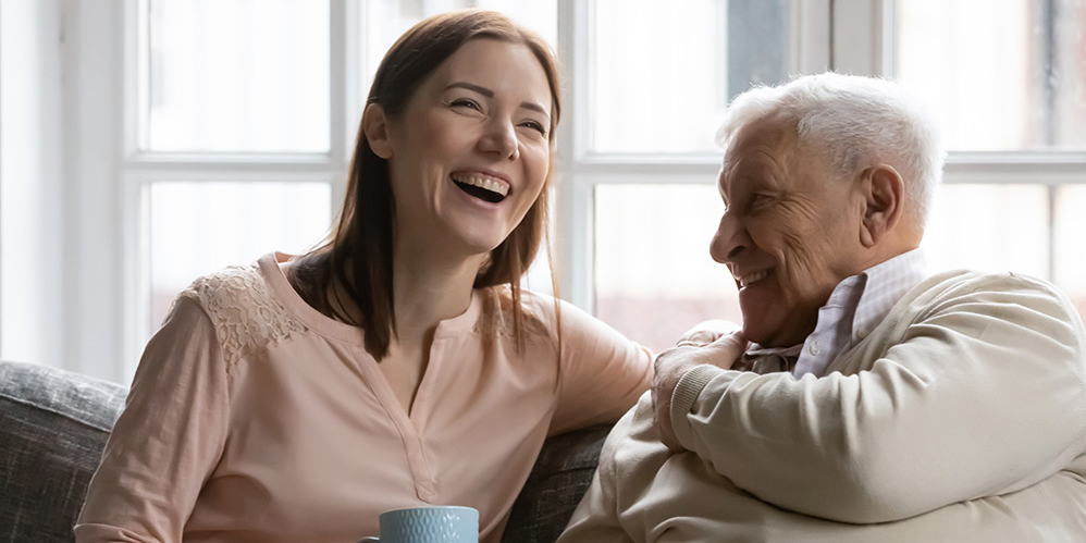 Laughing and smiling care worker woman with senior man