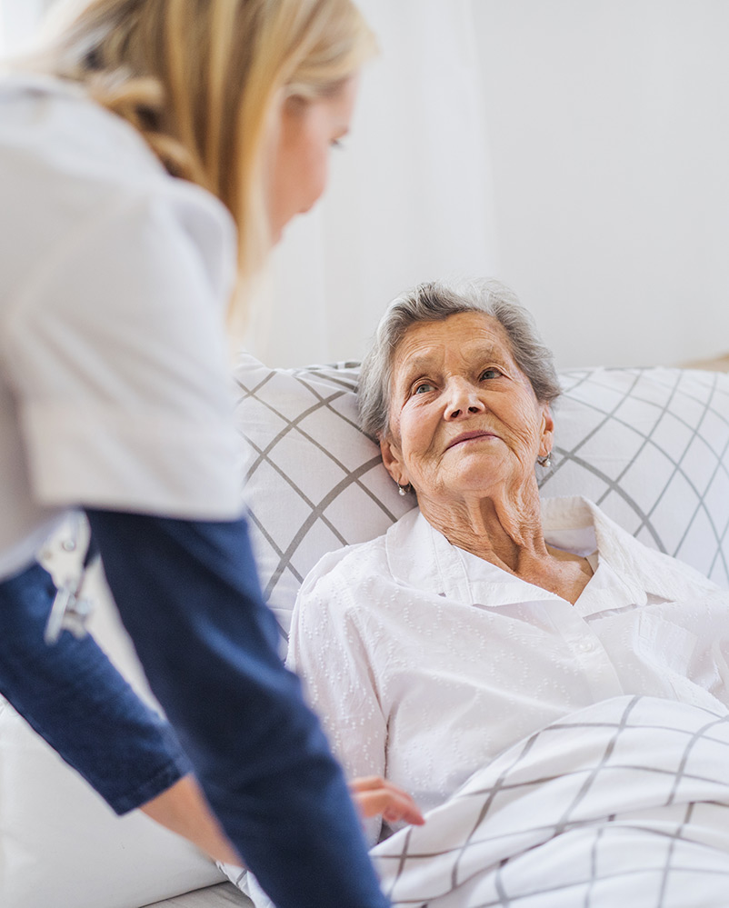 Care worker looking after senior woman in bed