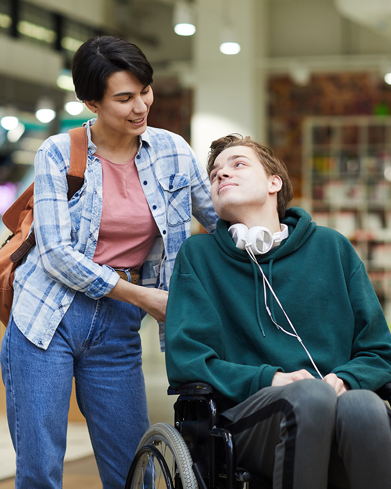 Care worker woman with client young man in wheelchair