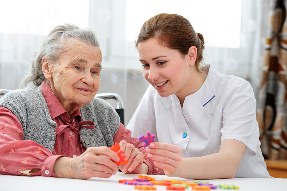 Care worker woman doing craft activity with woman with dementia